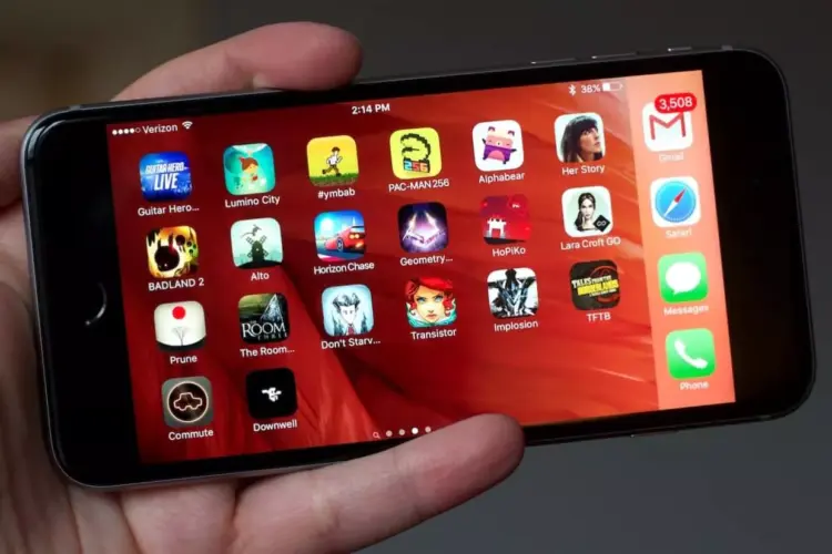 Tampilan homescreen iPhone yang dipegang tangan, dipenuhi berbagai ikon Game iPhone Gratis populer dan aplikasi media sosial.