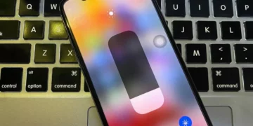 Layar iPhone menampilkan Control Center dengan slider kecerahan, menunjukkan opsi untuk True Tone aktif (Nyala) dan Night Shift.