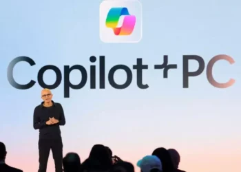 Satya Nadella mengumumkan Copilot+ PC di atas panggung dengan logo "Copilot+PC" besar.