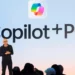 Satya Nadella mengumumkan Copilot+ PC di atas panggung dengan logo "Copilot+PC" besar.