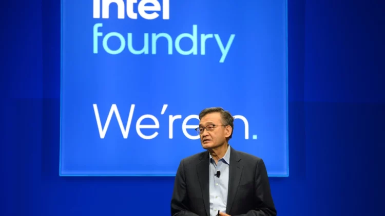 CEO Intel Pat Gelsinger berbicara di panggung dengan latar belakang "Intel Foundry We're In.", mendukung strategi privatisasi Intel untuk bersaing dengan TSMC.