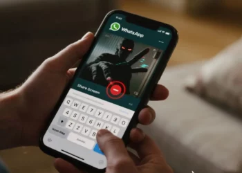 Seseorang memegang smartphone yang menampilkan modus penipuan share screen di WhatsApp, di mana peretas berusaha mengambil alih layar.