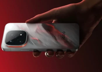 Sebuah tangan memegang flagship iQOO 15, menampilkan desain panel belakang yang bisa berubah warna dan modul kamera periskop dengan zoom 100X.