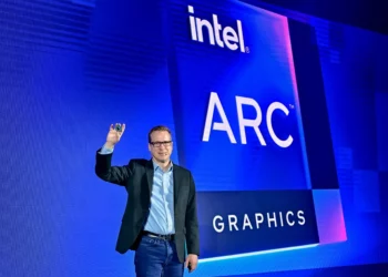 Eksekutif Intel di atas panggung memegang sebuah chip grafis, membahas masa depan dan nasib Intel Arc setelah kolaborasi dengan Nvidia.