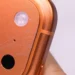 Close-up goresan mikro pada bodi iPhone 17 Pro berwarna oranye, mengilustrasikan kelemahan iPhone 17 Pro yang rentan terkelupas di bagian ujung kamera.