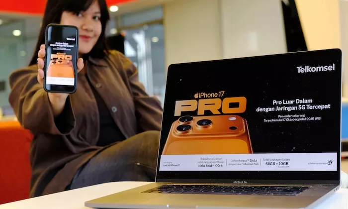 Wanita menunjukkan iPhone 17 Pro dan promosi pre-order Telkomsel di laptop