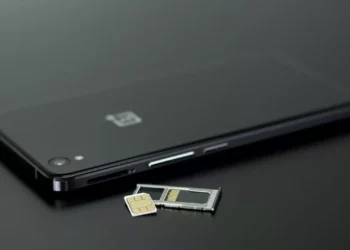 Baki Kartu SIM (tray) berisi kartu SIM dan kartu memori, terletak di samping smartphone berwarna hitam.