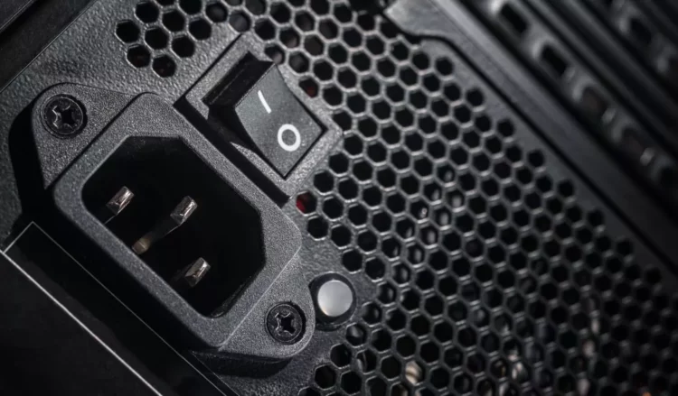 Seorang teknisi atau builder PC sedang memasang komponen PSU ke dalam casing PC gaming berwarna putih.