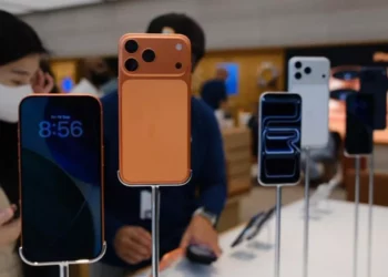 iPhone 17 (warna oranye) dan model lainnya dipajang di toko retail (iBox), dikelilingi oleh konsumen.