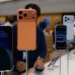 iPhone 17 (warna oranye) dan model lainnya dipajang di toko retail (iBox), dikelilingi oleh konsumen.
