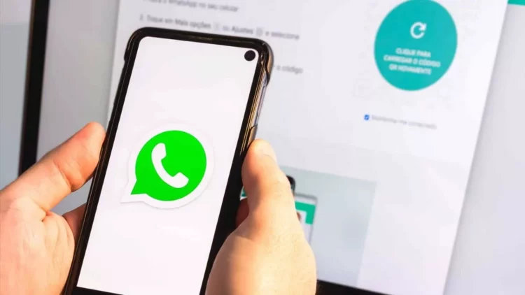 Logo aplikasi WhatsApp berwarna hijau ditampilkan di layar smartphone Android yang sedang dipegang.