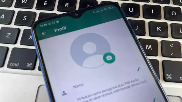 Layar 'Profil' WhatsApp di ponsel Android yang diletakkan di atas keyboard, menunjukkan foto profil default dan opsi untuk mengedit nama