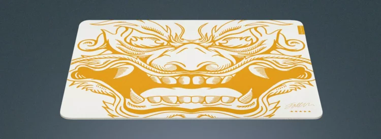 Razer Gigantus V2 Faker Edition Mouse Mat dengan desain topeng iblis Oni emas-putih dan tanda tangan Faker di sudut kanan bawah.