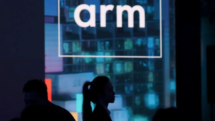 Logo perusahaan ARM ditampilkan di layar besar pada sebuah acara, menggambarkan peran penting prosesor ARM sebagai kekuatan tersembunyi di industri teknologi.