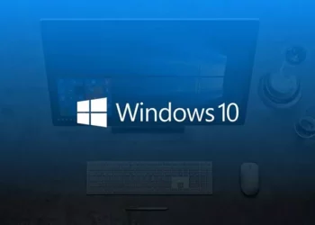 Logo Windows 10 di layar komputer, dilihat dari atas meja kerja