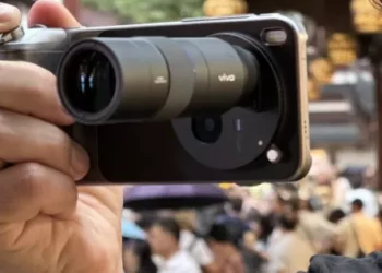 Pria menggunakan Vivo X300 Pro dengan lensa telephoto ZEISS 2.35x dari Photography Kit untuk memotret keramaian, meniru gaya kamera DSLR
