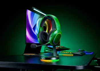 Headset gaming Razer Phantom Collection berwarna hijau dengan stand RGB yang menyala terang di meja hitam.