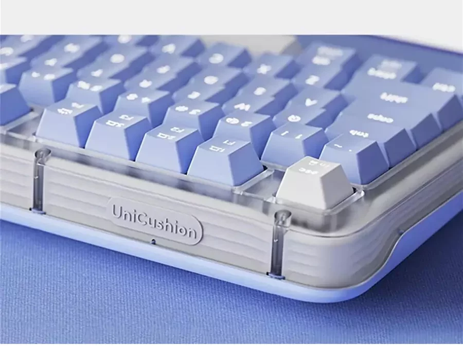 Close-up bagian samping dan tombol keyboard Logitech Alto Keys K98M berwarna biru muda, menyoroti tulisan 'UniCushion' pada bagian gasket.