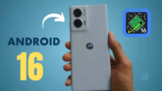 Tangan memegang smartphone Motorola berwarna abu-abu, dengan logo Android 16 di latar belakang biru terang dan ikon aplikasi Android 16 di sudut kanan atas.