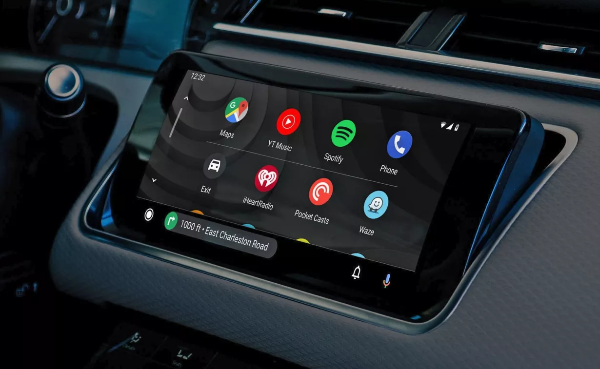Layar head unit mobil yang menampilkan antarmuka utama Android Auto dengan ikon aplikasi seperti Maps, YouTube Music, Spotify, dan Waze.