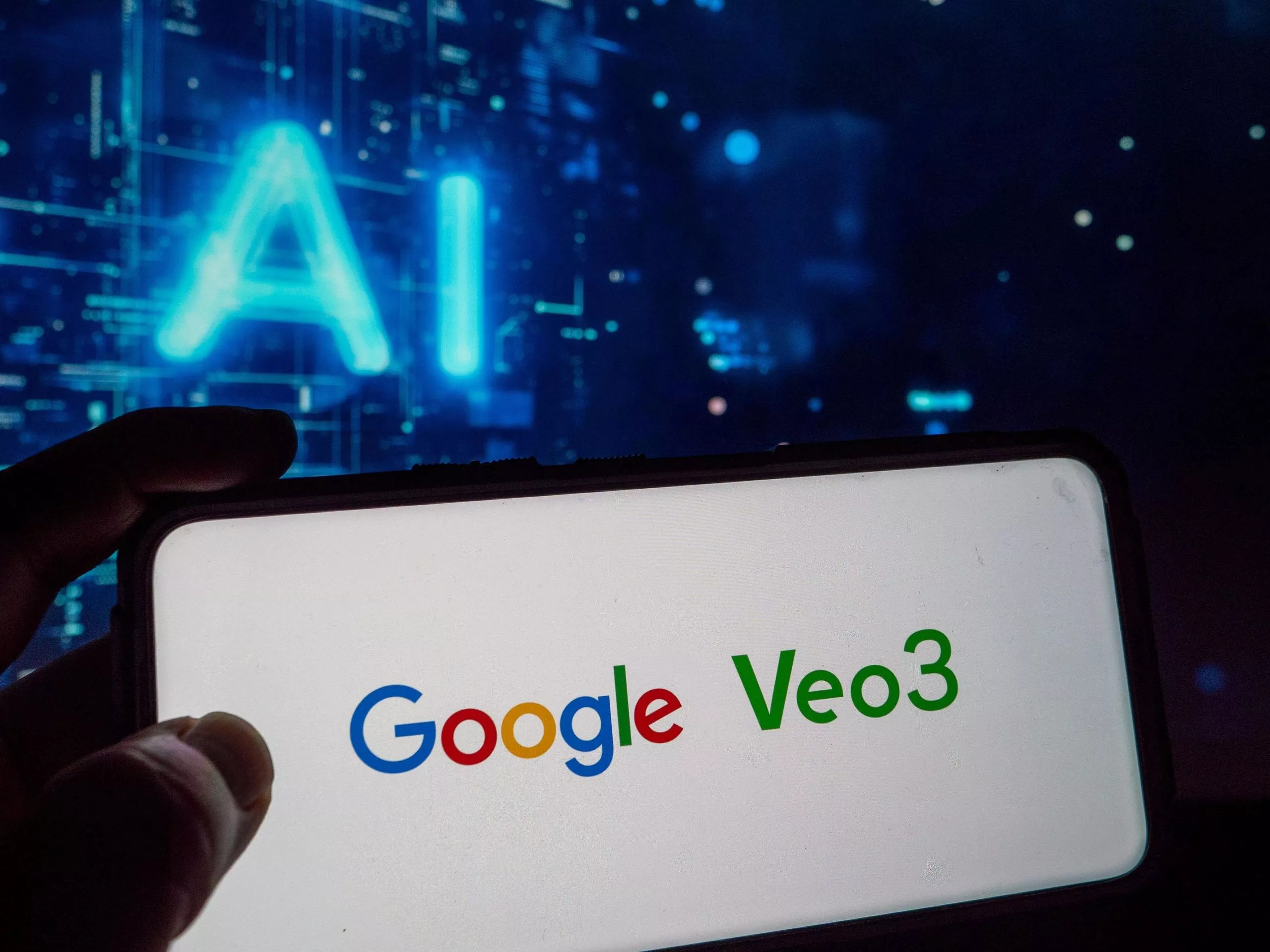 Tampilan layar smartphone yang memperlihatkan logo 'Google Veo3' di atas latar belakang layar komputer dengan tulisan AI bercahaya biru.