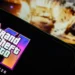 Logo Grand Theft Auto VI (GTA VI) dengan tanggal rilis 26 Mei 2026 ditampilkan di layar smartphone, terkait artikel pembahasan harga GTA VI.