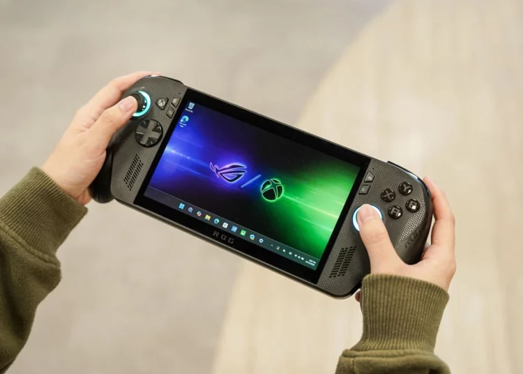 Sepasang tangan sedang memegang handheld gaming PC ROG Xbox Ally berwarna hitam, menampilkan antarmuka Xbox Fullscreen Experience yang intuitif di layarnya.