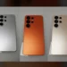 Unit dummy Samsung Galaxy S26 Ultra dalam tiga warna: perak, oranye cerah, dan emas/krem, dengan fokus pada bocoran warna oranye yang kontroversial.