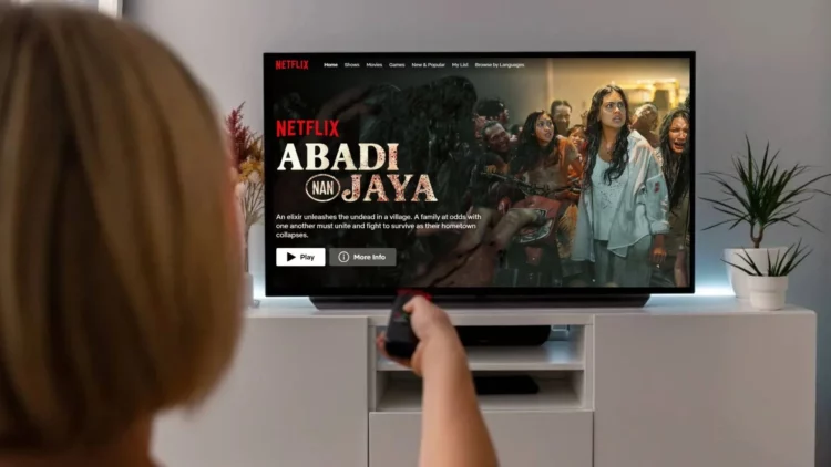 Ilustrasi cara nonton film Abadi Nan Jaya yang sedang trending di Netflix, menampilkan layar TV dengan halaman judul film dan seseorang yang memegang remote.