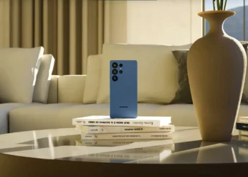 Samsung Galaxy S26 Ultra biru di meja kopi dengan sofa dan vas, mengilustrasikan rumor penundaan peluncuran