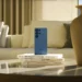 Samsung Galaxy S26 Ultra biru di meja kopi dengan sofa dan vas, mengilustrasikan rumor penundaan peluncuran