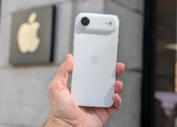 Sebuah tangan memegang konsep iPhone Air berwarna putih di depan logo Apple, menggambarkan spekulasi penurunan produksi iPhone Air.