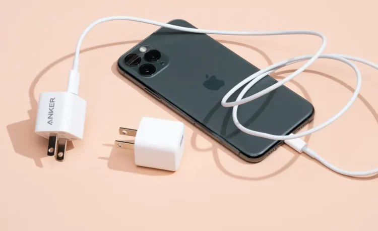 Sebuah iPhone sedang diisi daya dengan charger, sebagai ilustrasi kebijakan Apple yang menjadi awal mula era MacBook tanpa charger.