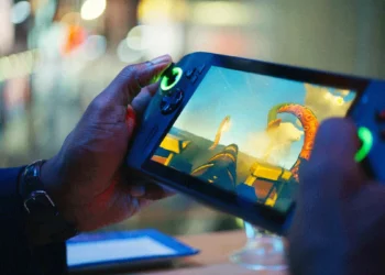 Seseorang sedang asyik bermain game petualangan di sebuah PC Gaming Handheld Terbaik pada malam hari, menampilkan layar yang cerah dan kontrol yang ergonomis.