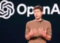CEO OpenAI, Sam Altman, berbicara di atas panggung dengan logo OpenAI di latar belakang.