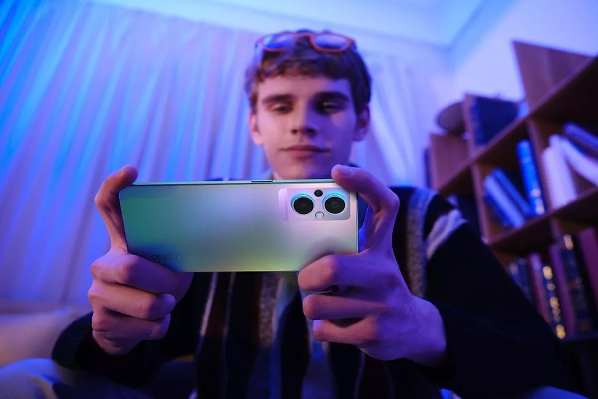 Tangan seseorang memegang smartphone Android yang sedang menampilkan game dengan grafis tinggi, menyimbolkan masalah lag.