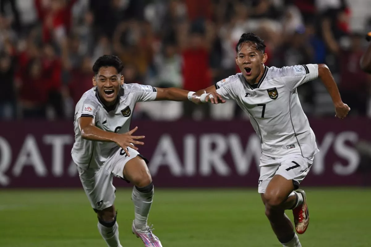Dua pemain Timnas Indonesia U-17, mengenakan jersey putih, berlari dengan ekspresi gembira di lapangan setelah mencetak gol.
