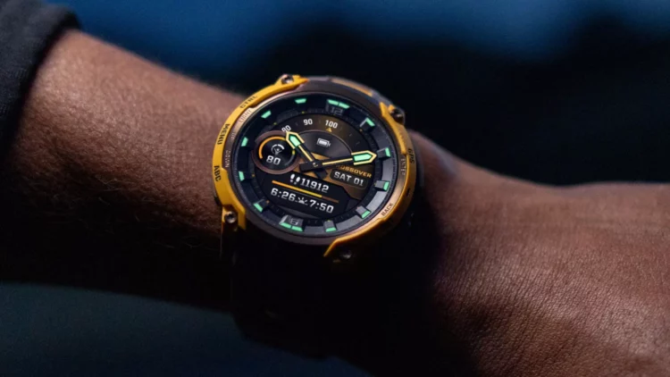 Close-up jam tangan Garmin Instinct Crossover AMOLED berwarna kuning di pergelangan tangan, menunjukkan tampilan hybrid digital dan analog.