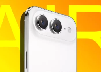 Close-up modul dual kamera belakang iPhone (model putih) dengan latar belakang oranye dan tulisan "AIR" besar, menyoroti desain kamera baru.