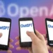 Tiga tangan memegang ponsel dengan tampilan aplikasi ChatGPT, di latar belakang buram logo OpenAI berwarna merah dan biru.