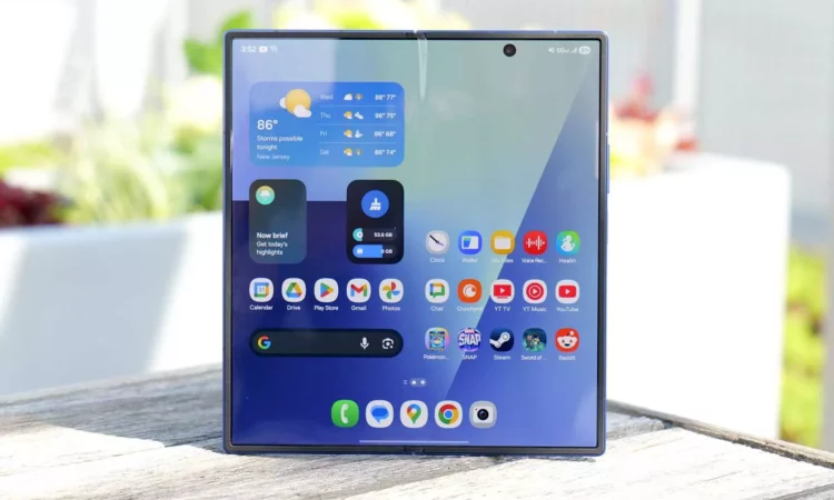Ponsel Samsung Galaxy Z Fold 7 terbuka, memperlihatkan antarmuka pengguna Android dengan widget cuaca dan beberapa aplikasi di layar utama.