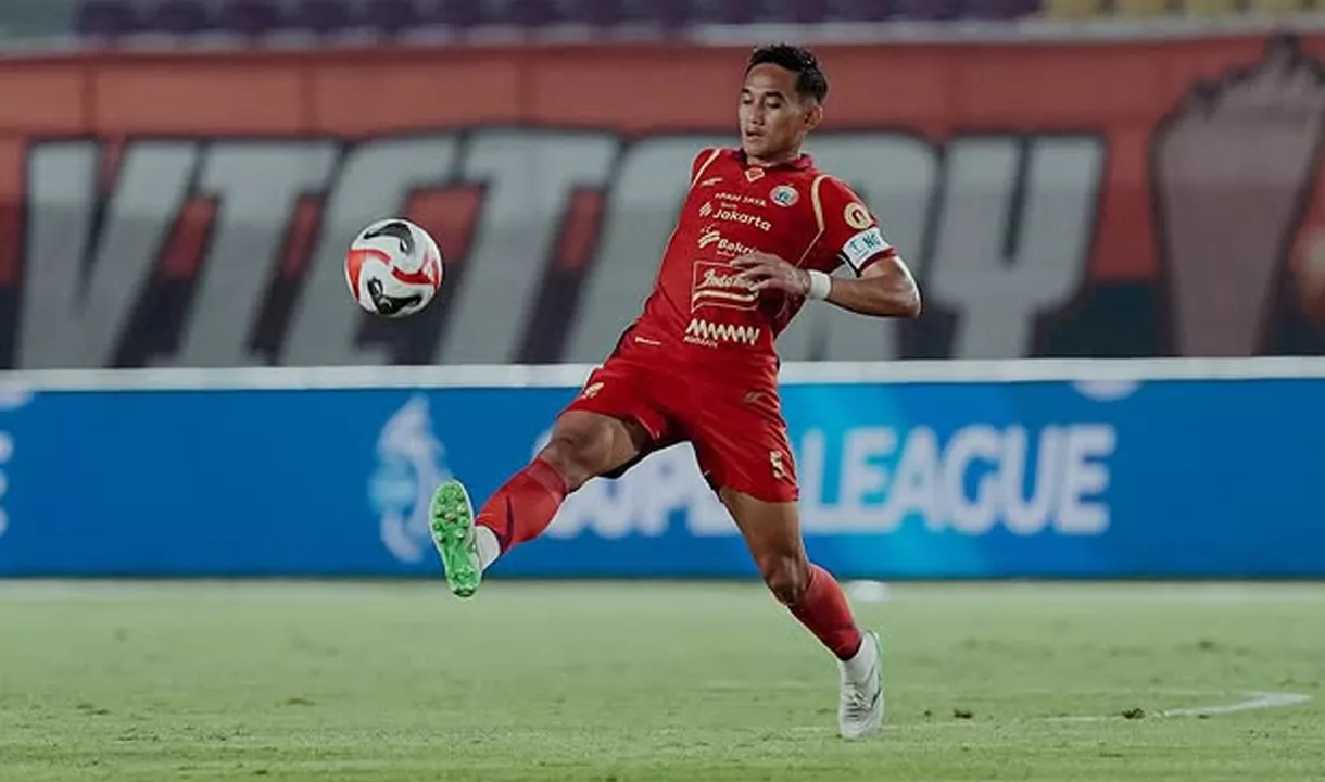 Rizky Ridho, pemain Persija Jakarta, sedang mengontrol bola di udara dengan seragam merah.