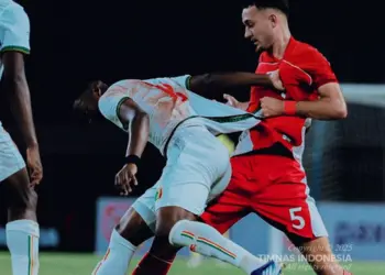 Pemain Timnas Indonesia (merah) sedang berduel fisik dengan pemain Timnas Mali (putih) untuk memperebutkan bola.