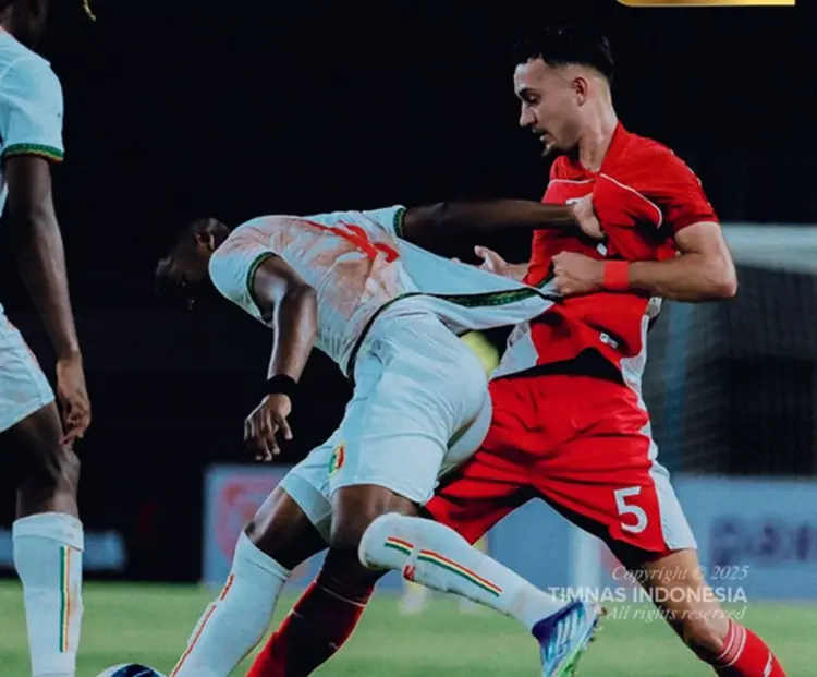 Pemain Timnas Indonesia (merah) sedang berduel fisik dengan pemain Timnas Mali (putih) untuk memperebutkan bola.
