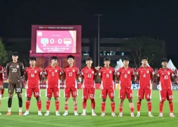 Skuad Timnas Indonesia U-17 berjejer di lapangan, mengenakan jersey merah, sebelum pertandingan melawan Brasil, dengan papan skor menunjukkan 0-0.