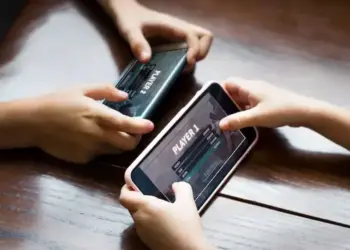 Dua anak bermain game multiplayer di ponsel cerdas secara bersamaan.