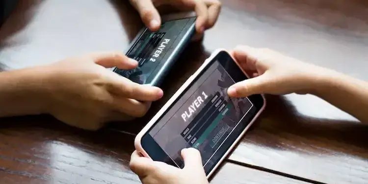 Dua anak bermain game multiplayer di ponsel cerdas secara bersamaan.