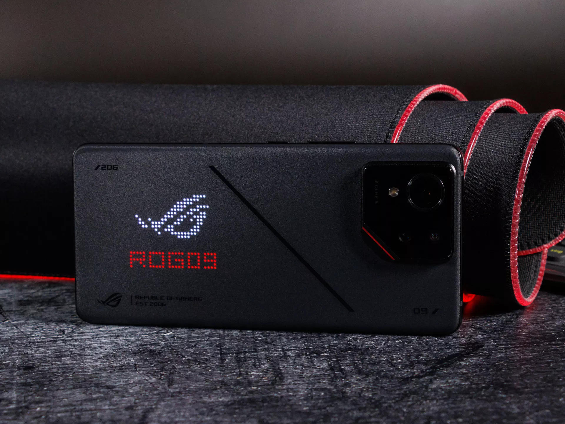 Tampilan belakang smartphone gaming Asus ROG Phone dengan logo ROG LED yang menyala.