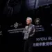 Jensen Huang, CEO NVIDIA, memegang chip AI saat presentasi NVIDIA Blackwell. Latar belakang menunjukkan slide tentang 'AI Superchip' dan 'Transformer Engine'.