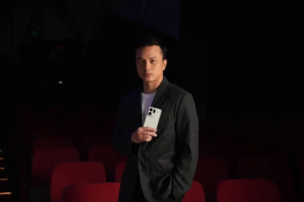 Aktor Nicholas Saputra memegang OPPO Find X9 Pro putih di dalam sebuah teater, menunjukkan desain modul Kamera 200MP Hasselblad yang jadi andalannya.